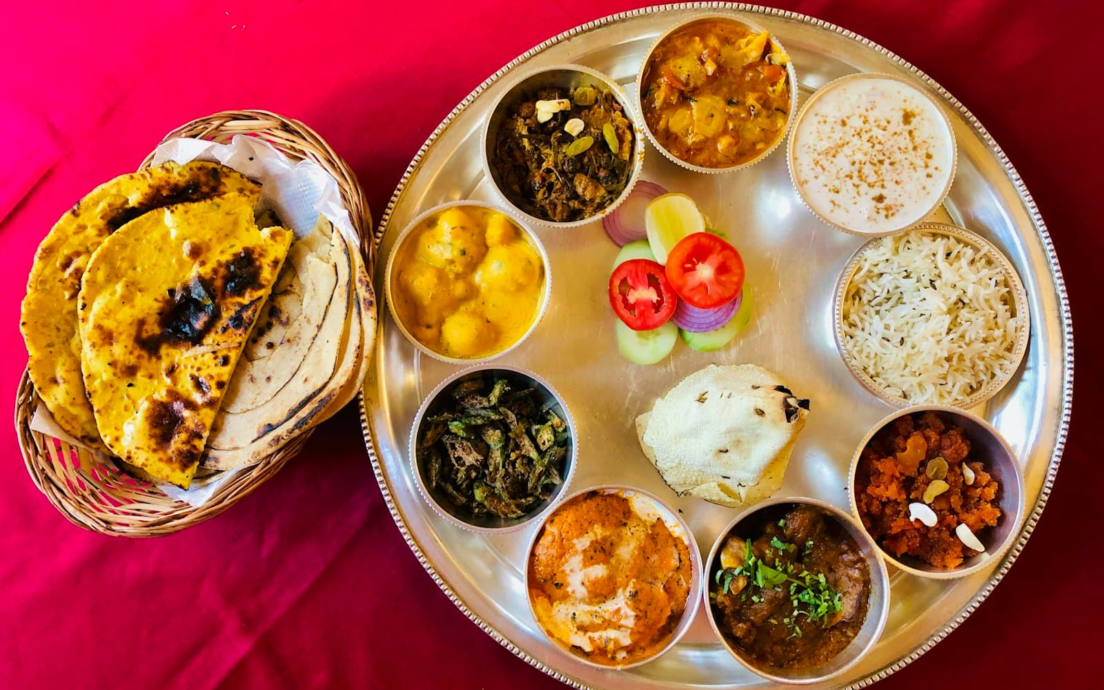 A plate of freshly steamed siddu, split open to show the walnut filling, with a bowl of dal and melted ghee alongside