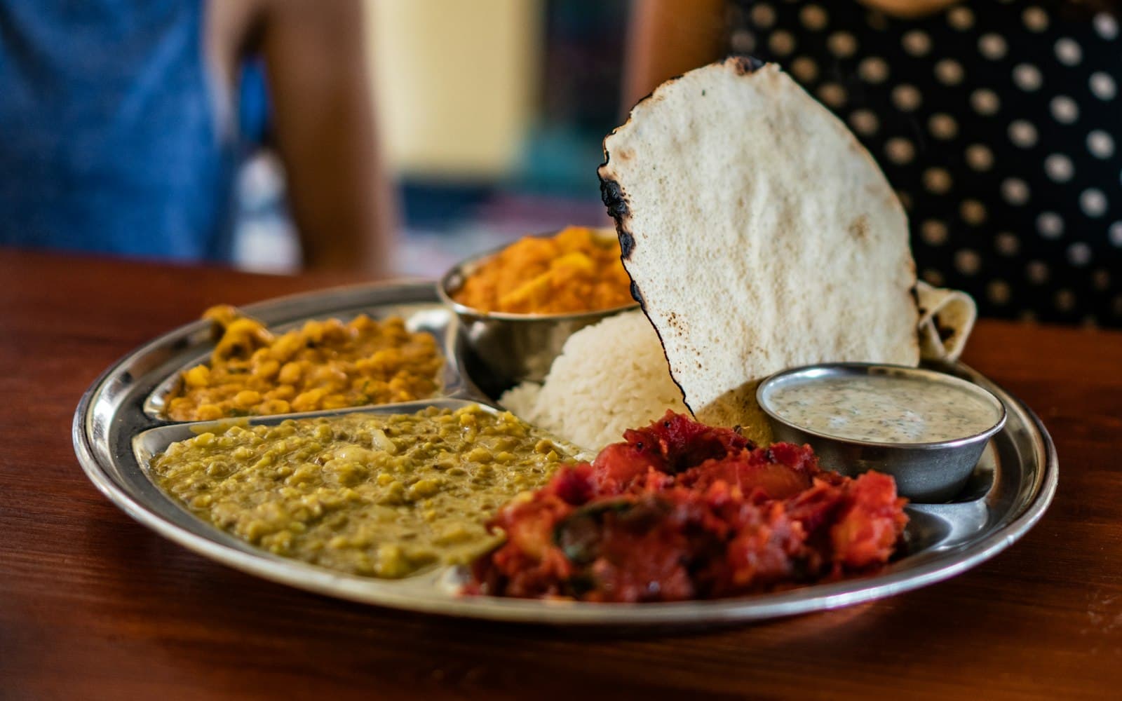 A plate of Himachali dham with rice, madra and khatta beside a steamed siddu at a village kitchen near Manali
