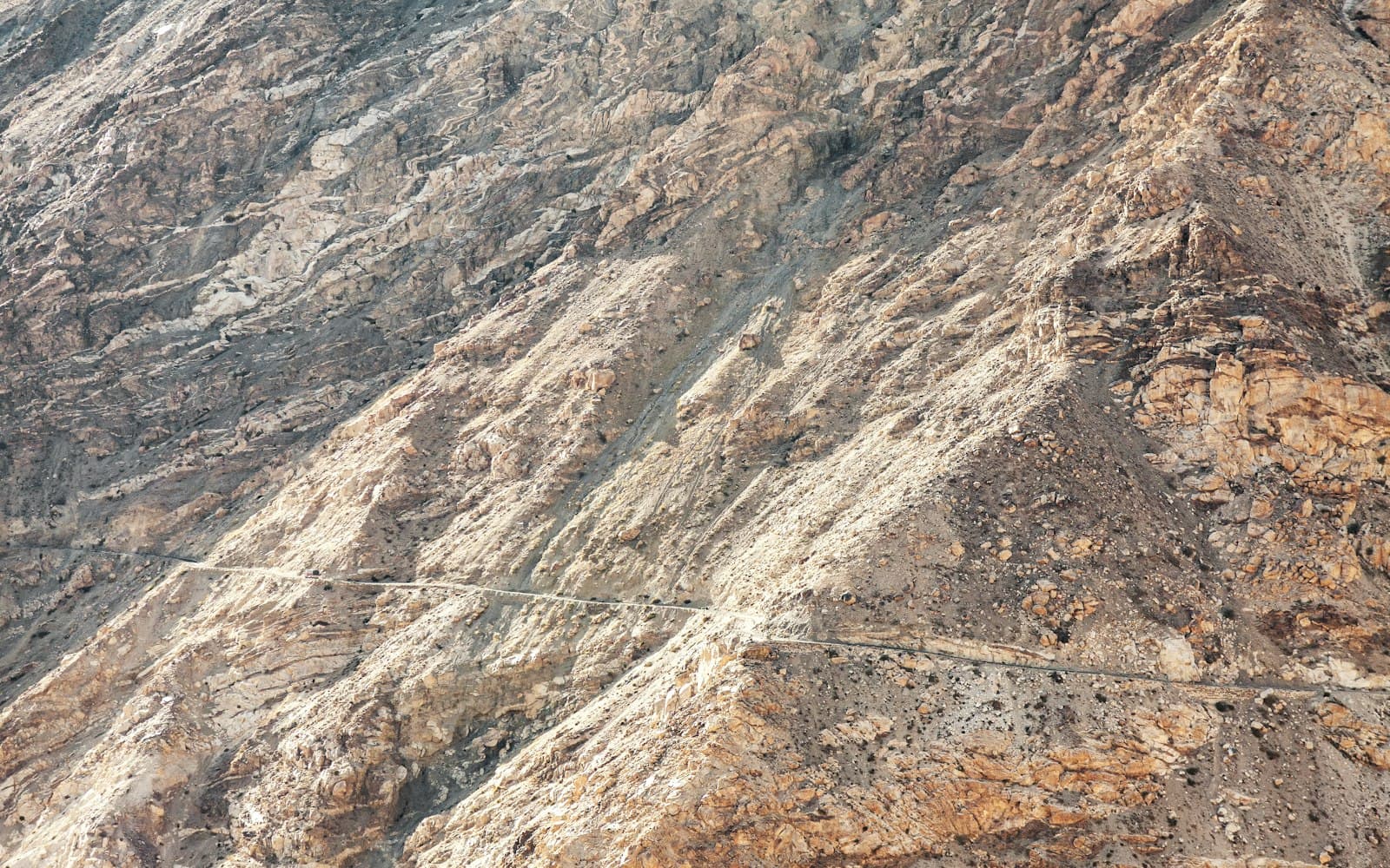 The Sissu waterfall dropping off a bare Lahaul cliff across the milky Chandra river, snow peaks above, after emerging from the Atal Tunnel