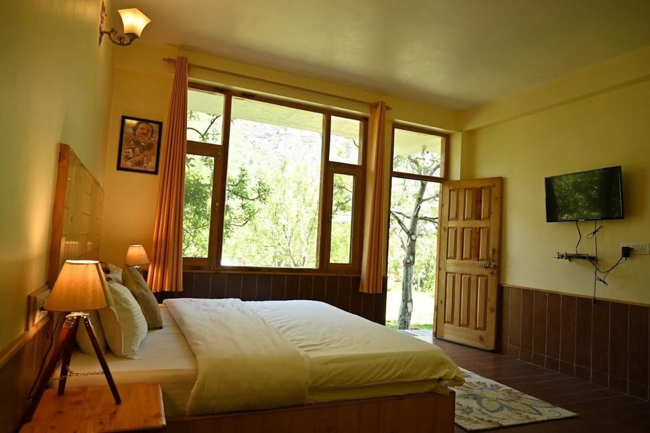 A wooden desk by a farmhouse window at Persimmon Farmstead, laptop open to morning light over the Kullu valley.